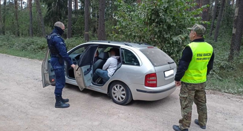 Zdjęcie policjanta i strażnika granicznego zatrzymujących pojazd przewożący nielegalnych migrantów/ SG