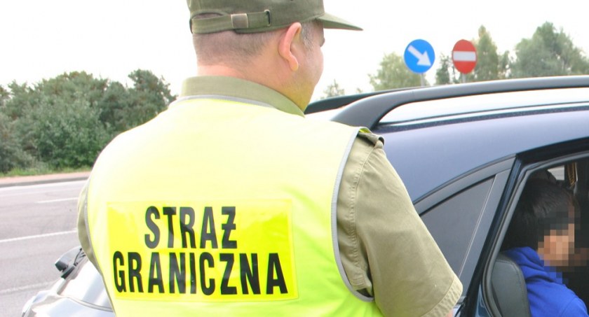 Zdjęcie strażnika granicznego zatrzymującego nielegalnych migrantów jadących w samochodzie/ SG