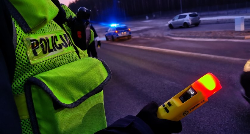 Zdjęcie policjanta trzymającego urządzenie do pomiaru alkoholu w wydychanym powietrzu/ podlaska.policja.gov.pl