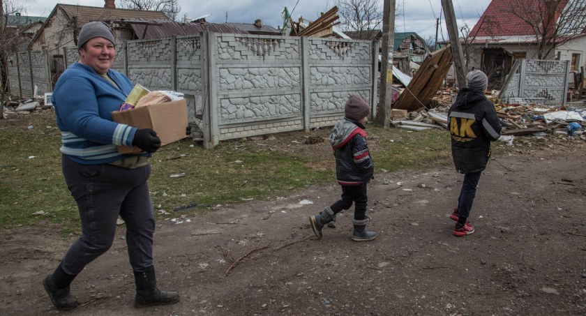 Zdjęcie kobiety i dzieci w zbombardowanej miejscowości na Ukrainie/ UNDP Ukraine