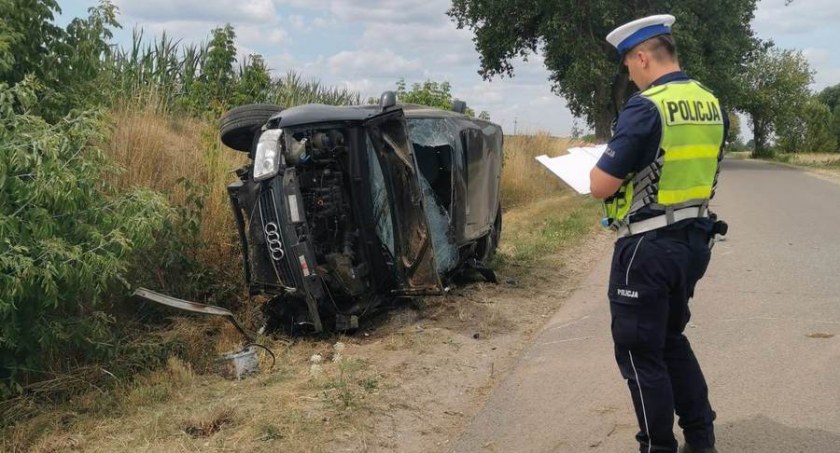 Zdjęcie przewróconego samochodu i policjanta na miejscu wypadku drogowego/ podlaska.policja.gov.pl