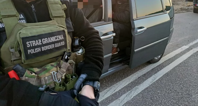 Zdjęcie strażnika granicznego przy samochodzie, którym przewożeni byli nielegalni migranci/ SG