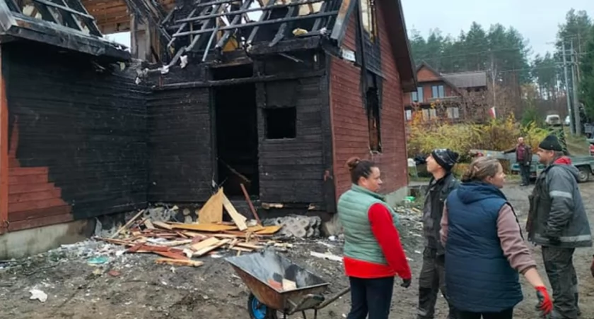 Zdjęcie ludzi na tle spalonego domu/ powiatbialostocki.pl