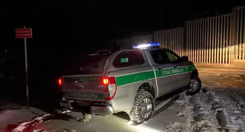 Zdjęcie pojazdu Straży Granicznej nocą pod zaporą oddzielającą od Białorusi/ SG