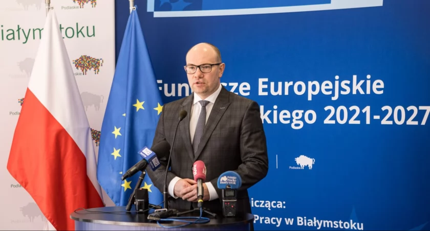 Zdjęcie marszałka Artura Kosickiego na tle flag/ podlaskie.eu