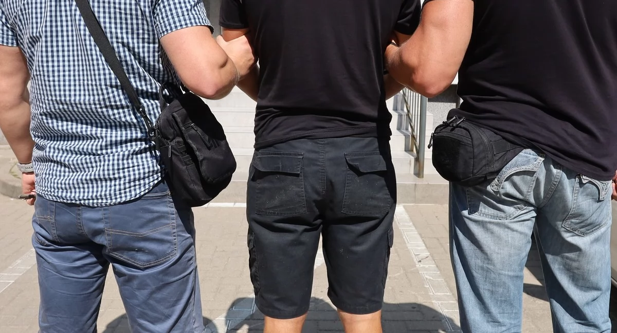 Zdjęcie policjantów prowadzących zatrzymanego mężczyznę/ podlaska.policja.gov.pl