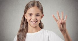 Headshot teenager girl showing 4 fingers on grey background